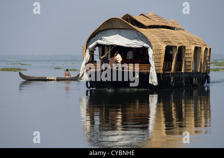 Ein Tourist-Hausboot auf den Backwaters von Kerala Indien mit dem Kanu im Hintergrund Stockfoto