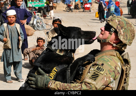 Ein Sergeant der US-Armee bekommt einen neuen Anstrich vertragen von seinen militärischen Gebrauchshund, Nero wie Kinder vor Ort in der Stadt Kandahar, Afghanistan am 3. Oktober 2012 aussehen Stockfoto