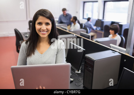 Frau mit Laptop während andere Arbeiten am Computer Stockfoto