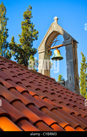 Glocke auf dem Dach der Kirche mit orange Fliesen bedeckt Stockfoto