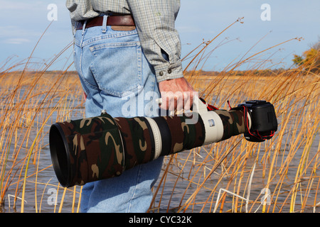 Professioneller Fotograf mit einem getarnten Canon Superteleobjektiv und DSLR. Stockfoto