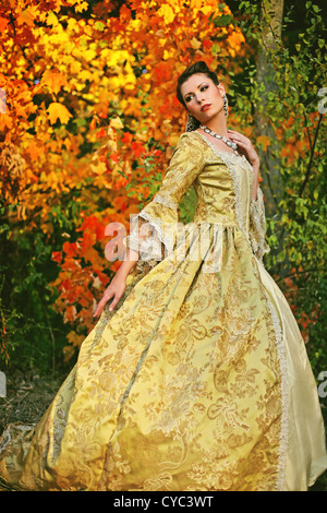 Eine hübsche junge Frau in ihren späten Teens oder in frühen 20er Jahren eine schöne verkleidet mit bunten Herbst Bäume Stockfoto