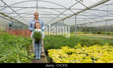 Gärtner und Enkelin hält eine große Topfpflanze Stockfoto