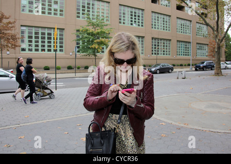 Frau mit Smartphone in Astoria, Queens, New York City, 26. Oktober 2012 © Katharine Andriotis Stockfoto