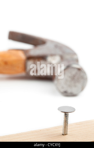 Halbe Nagel in ein Brett und einem Hammer hinter stecken Stockfoto