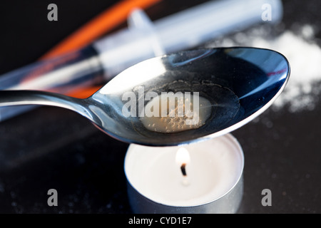 Heroin wird in einem Löffel über einer Kerze gekocht Stockfoto