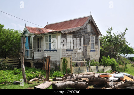 Blauer Himmel Blick kleines Holzhaus, mit weißen verwitterte Farbe Planken Wände und rote Metalldach, Luv, Carriacou, West Indies Stockfoto