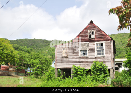 Blauer Himmel weiße Wolken anzeigen Holzhaus im grünen Rasen Garten des Grundstückes unter grünen Bergrücken, Luv, Carriacou, West Indies Stockfoto