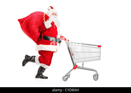 Santa Claus mit einer Tasche auf der Schulter drücken einen leeren Einkaufswagen isoliert auf weißem Hintergrund Stockfoto