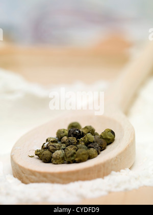 Nahaufnahme Detail einige grüne Peper Samen, platziert auf einem hölzernen Löffel, auf einem Bett aus Mehl Stockfoto