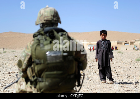 Ein lokalen afghanischen jungen beobachtet, wie Mitglieder der US Army und Navy ihren Weg durch sein Dorf 26. September 2012 im Pur Chaman District, Provinz Farah, Afghanistan. Die provinzielle Rekonstruktion Team Farah markiert die erste Zeit-Koalition, die Kräfte zum Bezirk Pur Chaman in mehr als einem Jahr gewesen. Stockfoto