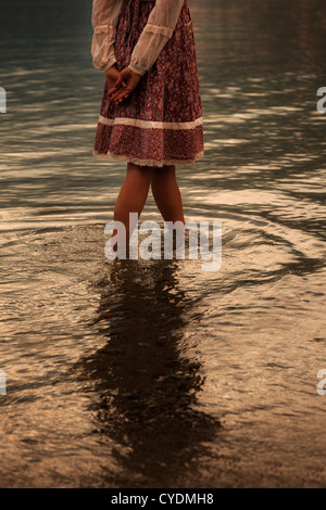 ein Mädchen in ein Vintage-Kleid ist im Wasser spazieren. Stockfoto