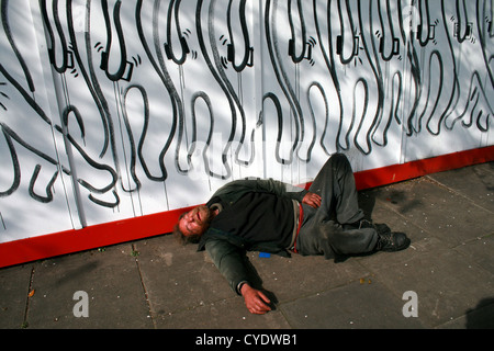 Betrunkener Mann schlafen auf einem Bürgersteig in der Nähe von Brick Lane, London Stockfoto