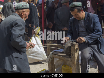 Uyghur Männer schärfen ein Messer, Opal Dorfmarkt, Xinjiang Uyghur autonome Region, China Stockfoto