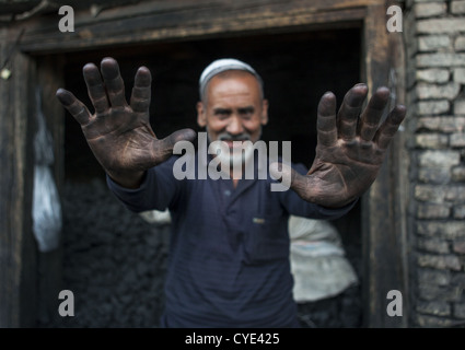 Uyghur Männer verkaufen Kohle zeigt seine Hände fallenden Staub, Yarkand, Xinjiang Uyghur autonome Region, China Stockfoto