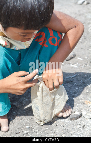 Scavenger-jungen auf der Suche nach elektronischen Bauteile auf der Dump-Website unter Stung Meanchey in Phnom Penh, Kambodscha Stockfoto