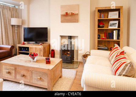 Zeitgenössische Wohnzimmer mit neutralen Farben, Holzofen und Holzboden. Fotografen eigene Grafik auf Wand und Bücherregal. Stockfoto