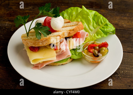 Foto von leckeren Toast gefüllt mit Käse und Schinken mit Salat und Petersilie Stockfoto