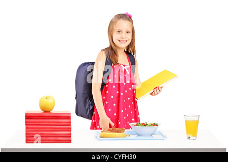 Ein Schulmädchen mit Tasche und Buch, die Vorbereitungen für das Mittagessen, die isoliert auf weißem Hintergrund Stockfoto