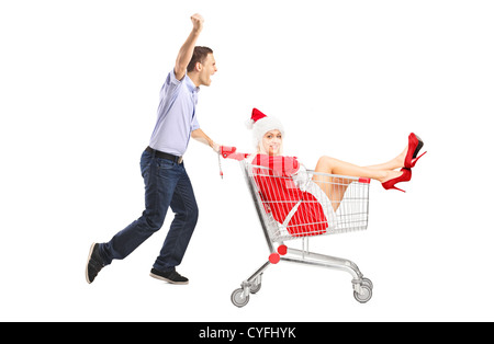 Glücklicher Kerl schob ein Warenkorb und ein Weibchen im Weihnachtskostüm isoliert auf weißem Hintergrund Stockfoto