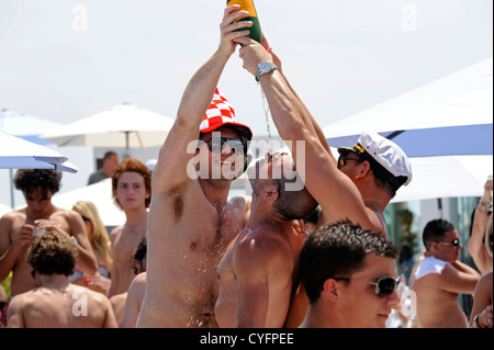 Britische Partygänger Gießen Flaschen Champagner übereinander im Beach Club Champagner versprühen Partei Stockfoto