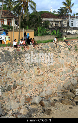 Junge Leute sitzen auf der Außenseite Wand Galle Fort in Sri Lanka. Stockfoto