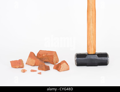 Vorschlaghammer und defekte Ziegel auf weißem Hintergrund Stockfoto