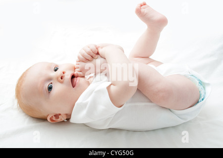 Cute Baby Girl saugen ihre Zehen auf weißem Hintergrund Stockfoto