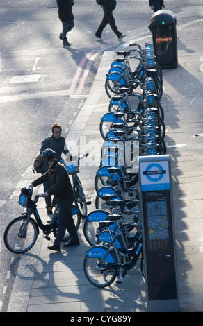 Morgen Pendler Fuß vorbei Reihe von Boris Leihräder in London Straße mit Docking-Fahrrad Radfahrer als andere Radfahrer-Blätter Stockfoto