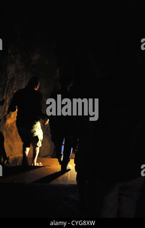 Menschen klettern Treppe hinunter in die Dunkelheit. Stockfoto