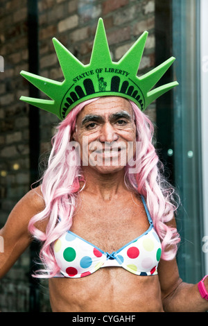 lächelnd gegerbt mittleren gealterten männliche Transvestit für Halloween Polka Dot Bikini rosa Perücke & Statue of Liberty Spikes Krone bekleidet Stockfoto