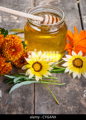 Honig und Blumen auf Holztisch Stockfoto