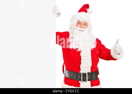 Ein glücklich Santa Claus steht neben einer leeren Plakatwand und einen Daumen aufgeben Stockfoto