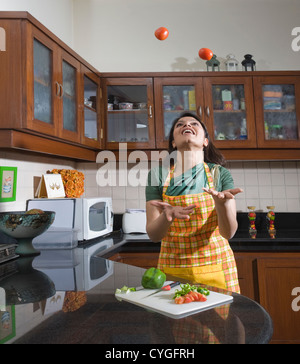 Frau jongliert mit Tomaten in der Küche Stockfoto