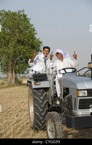 Landwirt tanzen auf einem Traktor mit seinem Sohn Stockfoto