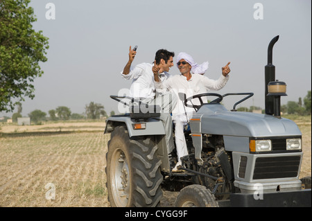 Landwirt tanzen auf einem Traktor mit seinem Sohn Stockfoto