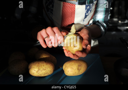 Junge Frau der 20er Jahre Altersgruppe Vorbereitung Schaben Kartoffelschälen bereit für das Kochen in der Küche Stockfoto