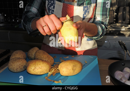 Junge Frau der 20er Jahre Altersgruppe Vorbereitung Schaben Kartoffelschälen bereit für das Kochen in der Küche Stockfoto