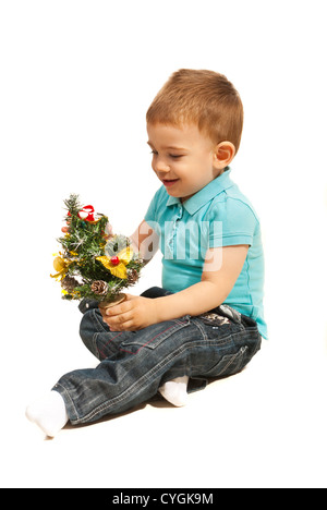 Lächelnd kleiner Junge spielt mit Miniatur-Weihnachtsbaum isoliert auf weißem Hintergrund Stockfoto