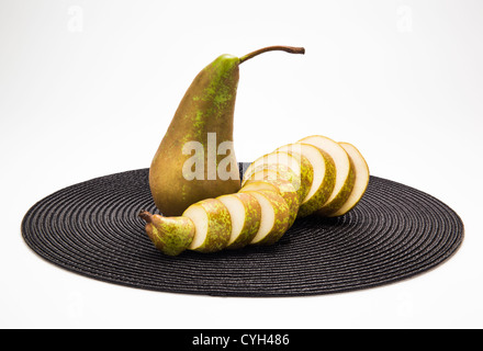 Eine ganze Birne und eine Birne auf schwarz Tischset in Scheiben geschnitten Stockfoto