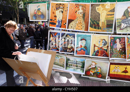 Frau suchen original kopierten Kunst Arbeit Ölgemälde zu verkaufen, El Rastro Flohmarkt Madrid Spanien Stockfoto