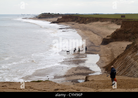 Wanderer und Hund am Strand von Happisburgh. Norfolk. Tide eingreift und weiterhin schrittweise die Klippen erodieren. Norfolk. East Anglia. Stockfoto