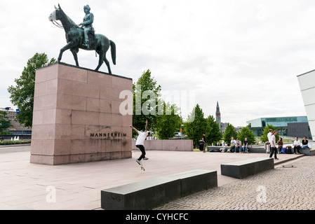 Teenager Skateboard vor dem Museum der zeitgenössischen Art Kiasma und die Marchal Mannerheim-Statue in Helsinki, Finnland Stockfoto