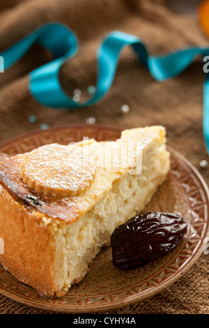gebackene Rum und Rosinen Cheesecake Wüste auf einen natürlichen Stoff mit blauen Band und Termine während der Feier Stockfoto