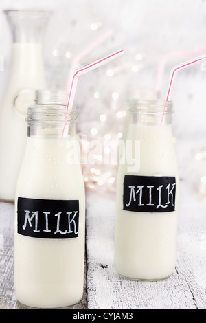 Glasflaschen von Milch mit Strohhalmen und antiken Milchflasche im Hintergrund. Geringe Schärfentiefe. Stockfoto