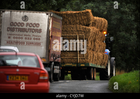 Verkehr stecken hinter einem Traktor mit einem Anhänger von Heu auf einer Straße in Gloucestershire UK Stockfoto