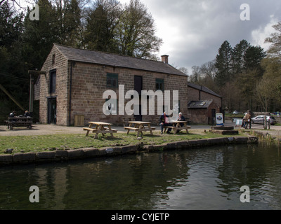 zwei Menschen sitzen auf einer Picknickbank am Cromford Kanal im englischen Derbyshire Peak District Stockfoto