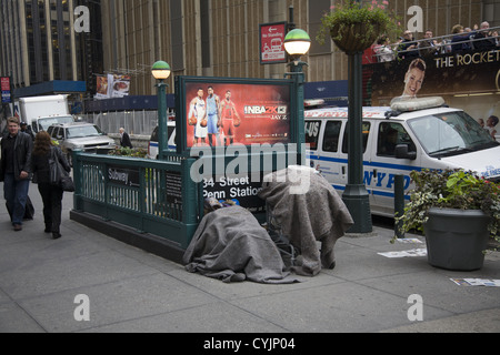 Schlafenden Obdachlosen Mann mit seinen Besitz gegen den Eingang zum u-Bahnhof 34th St. am 8th Avenue NYC abgedeckt Stockfoto