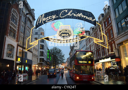 6. November 2012: Oxford Street Christmas Lights Sponsored by "Marmite Gold" Display zeigt ein Zeichen Tauchen in den Topf mit Marmite, während ein anderes Zeichen in eine Weihnachtsmütze in Bezug auf Marmite des lang andauernden Slogan "Sie entweder lieben oder hassen es" London, UK erbricht Stockfoto