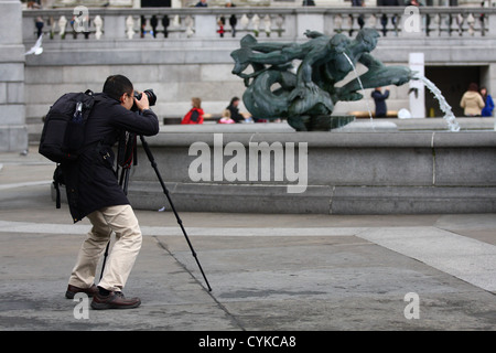 Ein Mann mit einem Stativ fotografieren am Trafalgar Square in London Stockfoto